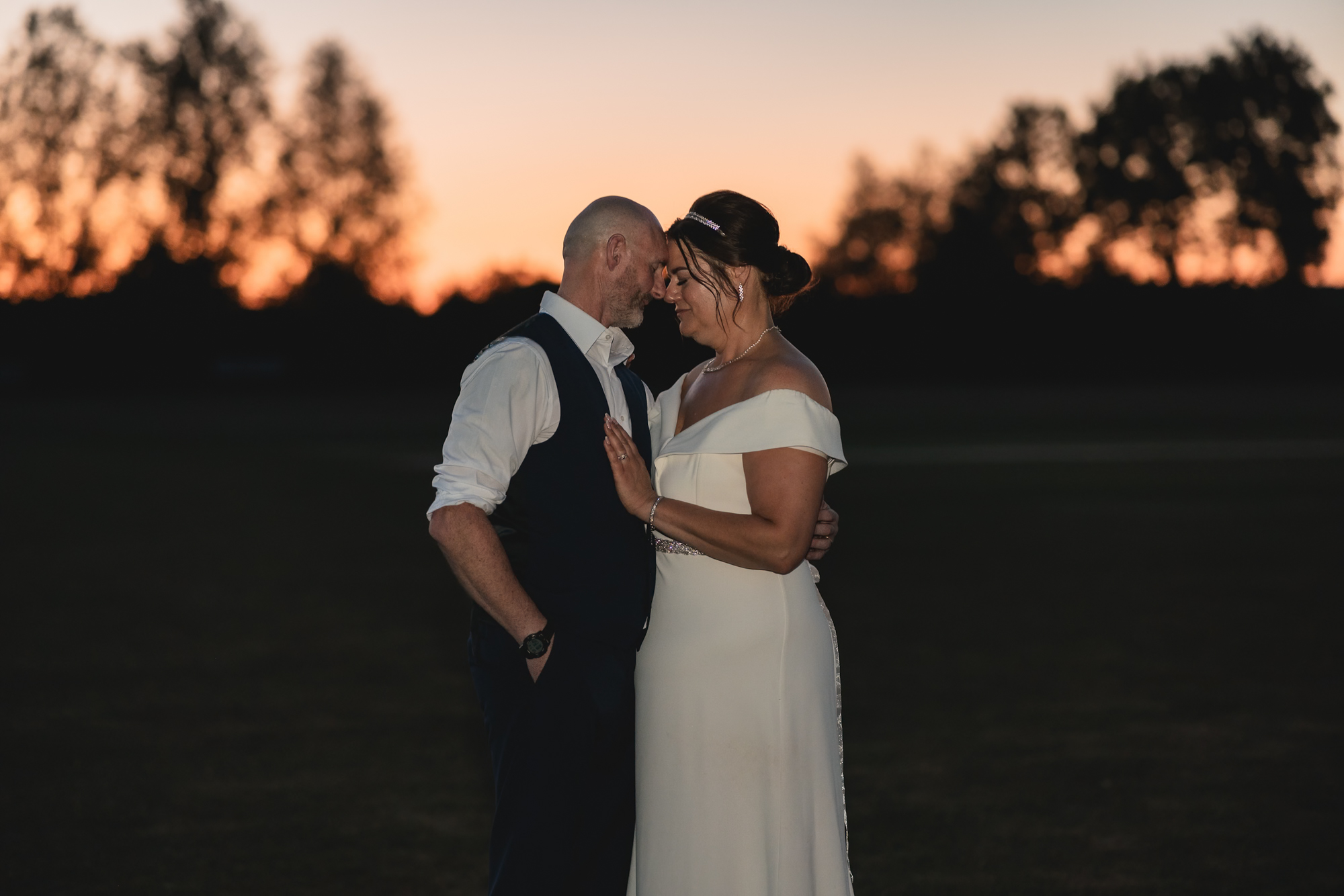 Bride and groom embracing at sunset during Yorkshire evening wedding portraits