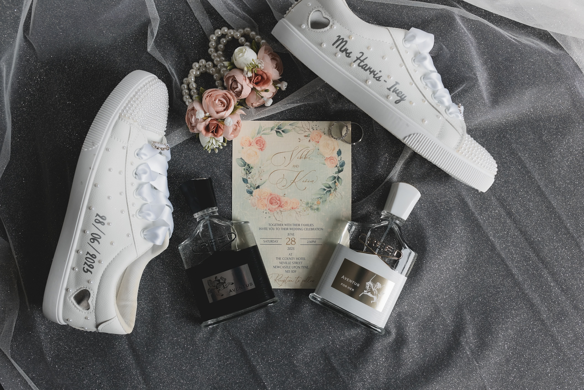 Wedding flat lay with personalised bridal trainers, wedding invitation, perfume bottles, flowers, and rings during bridal preparations