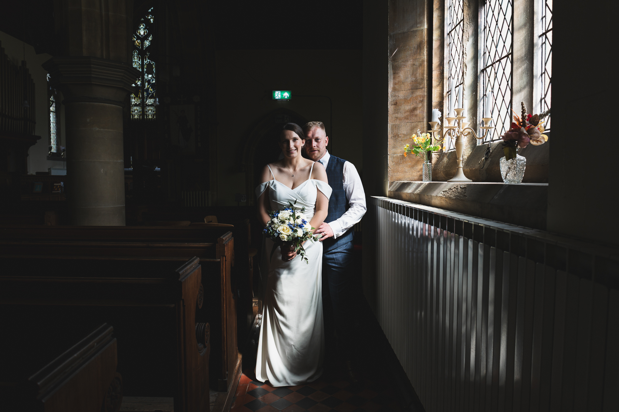 Creative documentary wedding portrait of bride and groom inside historic church with cinematic window light in Yorkshire UK
