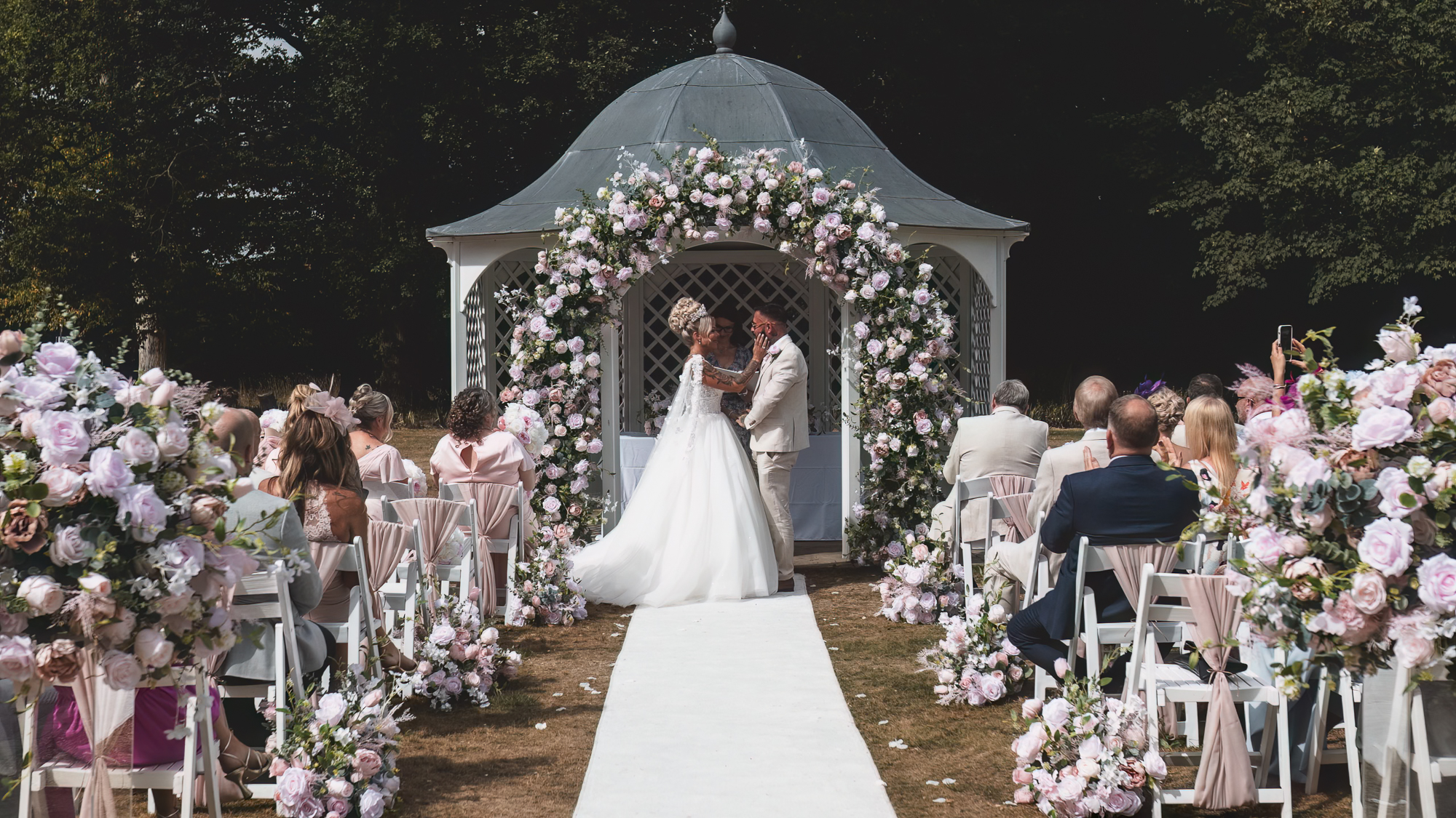 Guests and couple photographed from multiple angles during a wedding ceremony