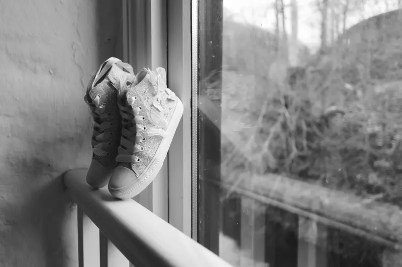 Black and white bridal trainers detail photo by window during wedding preparations
