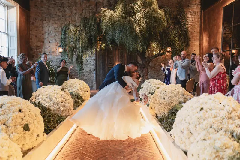 Dramatic wedding dip kiss during indoor ceremony celebration