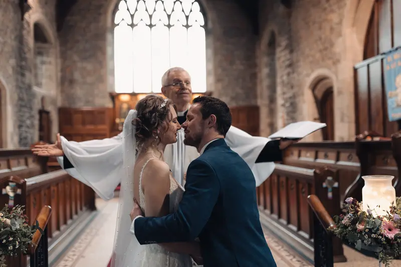Romantic first kiss during church wedding ceremony captured in cinematic style