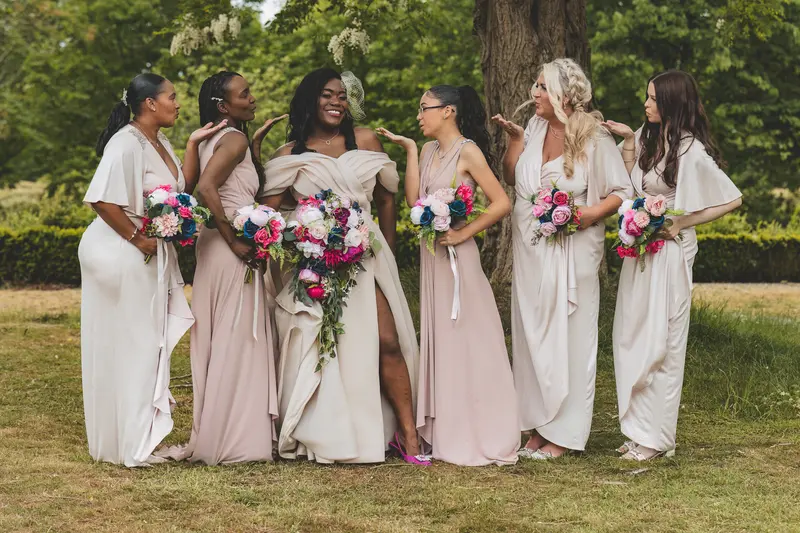 Bride and bridesmaids walking together with colourful bouquets during wedding portraits