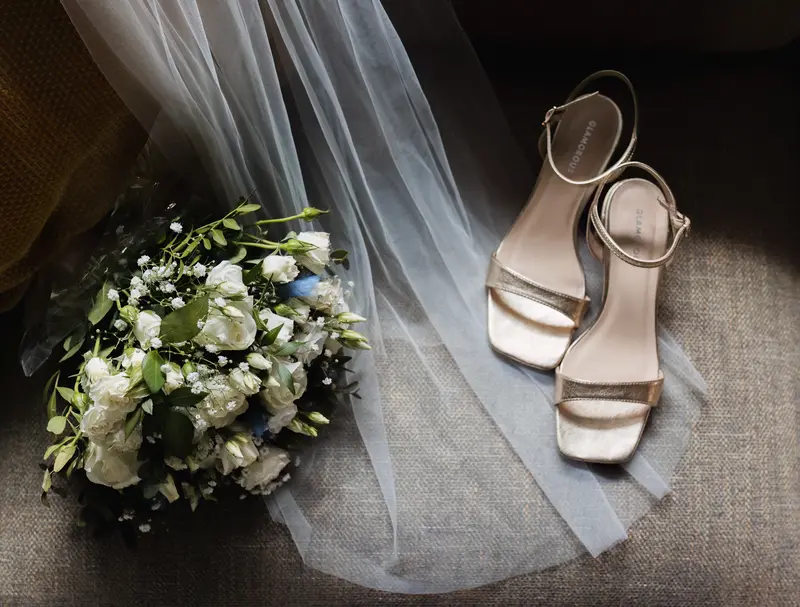 Elegant bridal bouquet and wedding heels detail shot with soft natural light