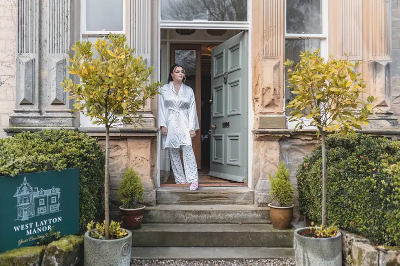 Bride standing outside the wedding venue in her bridal robe before getting ready