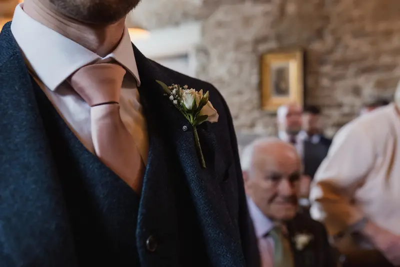 Close up groom boutonniere detail during rustic documentary wedding ceremony