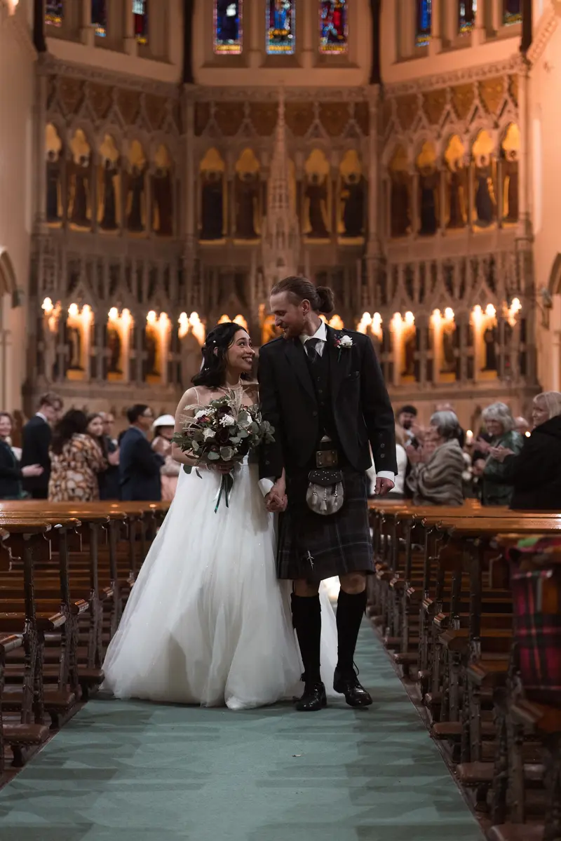 Newly married couple walking through church aisle in Yorkshire wedding venue, candid wedding photography