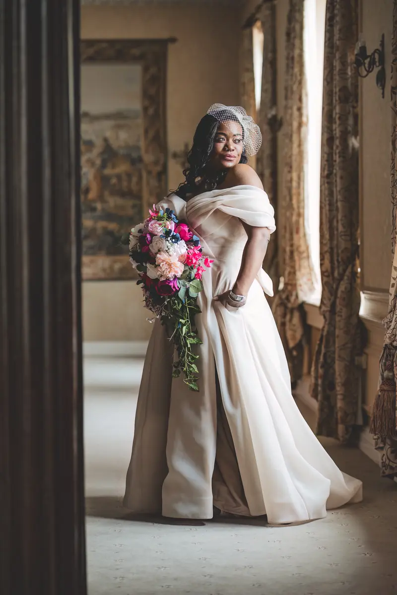 Elegant bridal portrait by the window with colourful wedding bouquet