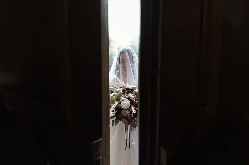 Cinematic bridal portrait through church doors by documentary wedding photographer Yorkshire