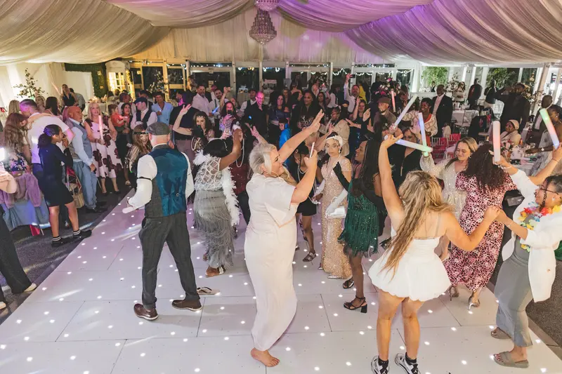 Bride and groom dancing with guests during a lively wedding reception celebration