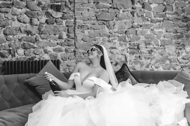 Bride relaxing with champagne before the ceremony during natural bridal preparations