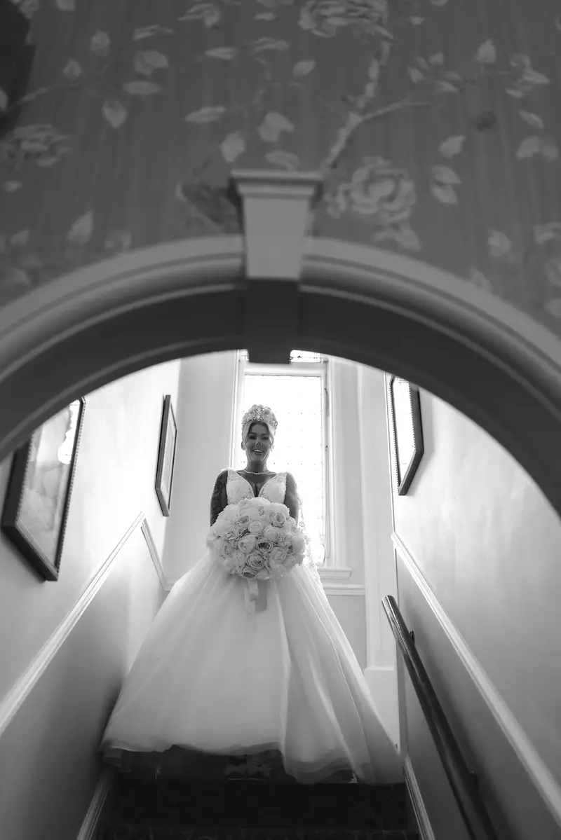 Black and white bridal portrait on staircase with bouquet and elegant wedding dress