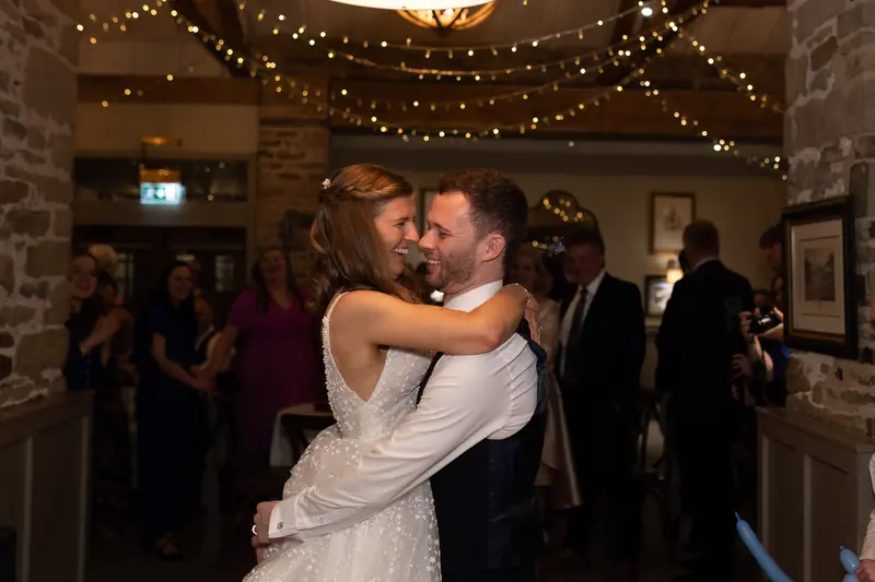 Emotional first dance documentary wedding photography with bride and groom embracing under fairy lights in Yorkshire venue