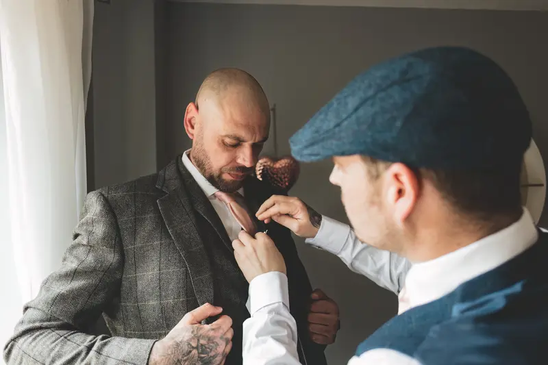 Groom and groomsman sharing a candid moment while getting ready before the ceremony