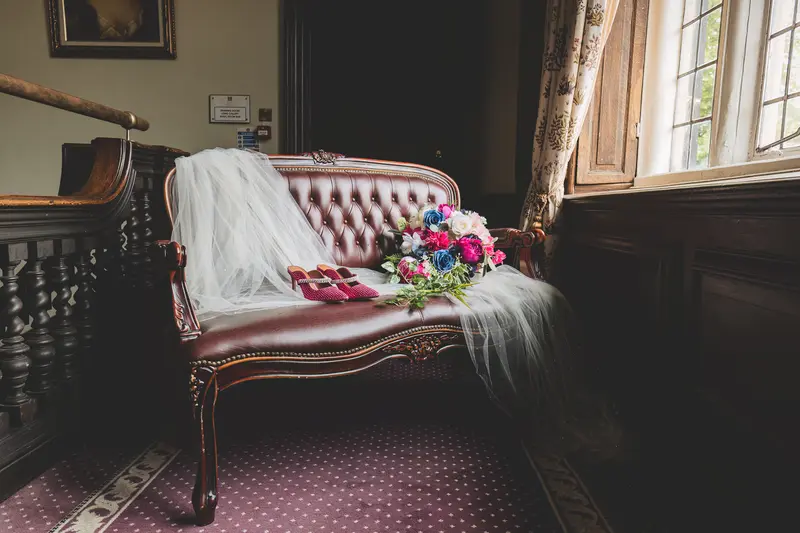 Bride’s wedding dress laid on a vintage sofa during bridal morning preparations