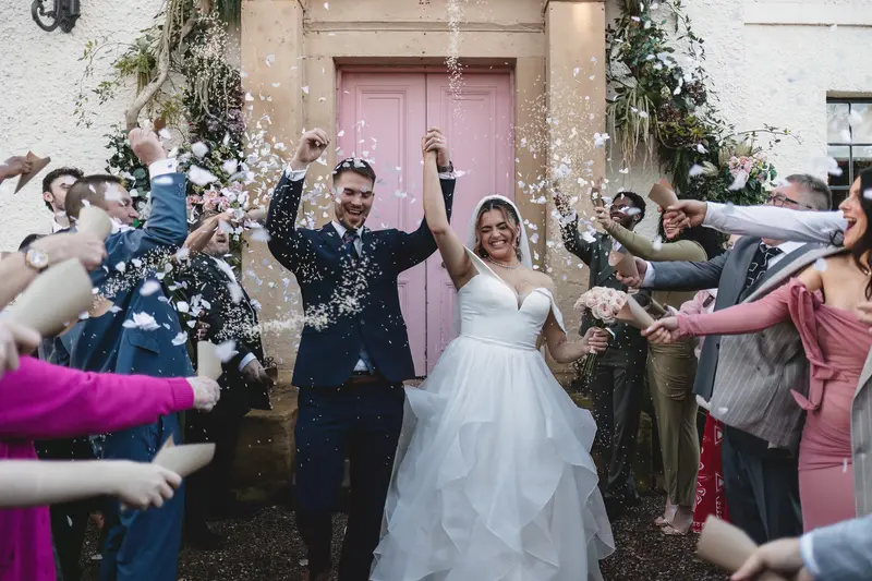 Documentary wedding confetti exit outside romantic venue entrance