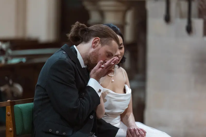 Groom kissing bride’s hand during intimate wedding ceremony, natural documentary wedding photography UK