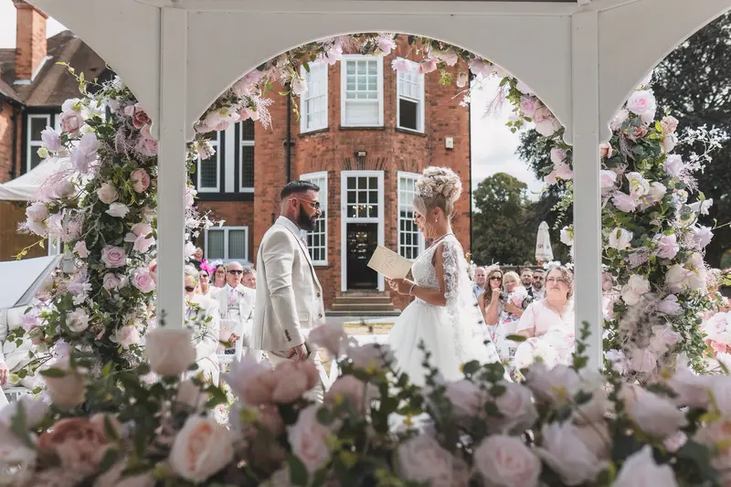 Outdoor wedding ceremony under floral arch at elegant countryside venue