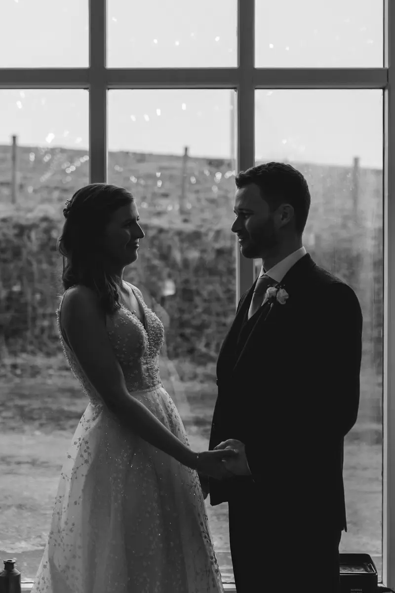 Black and white silhouette portrait of bride and groom holding hands during intimate Yorkshire wedding reception