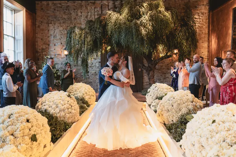 Romantic first kiss during elegant indoor wedding ceremony