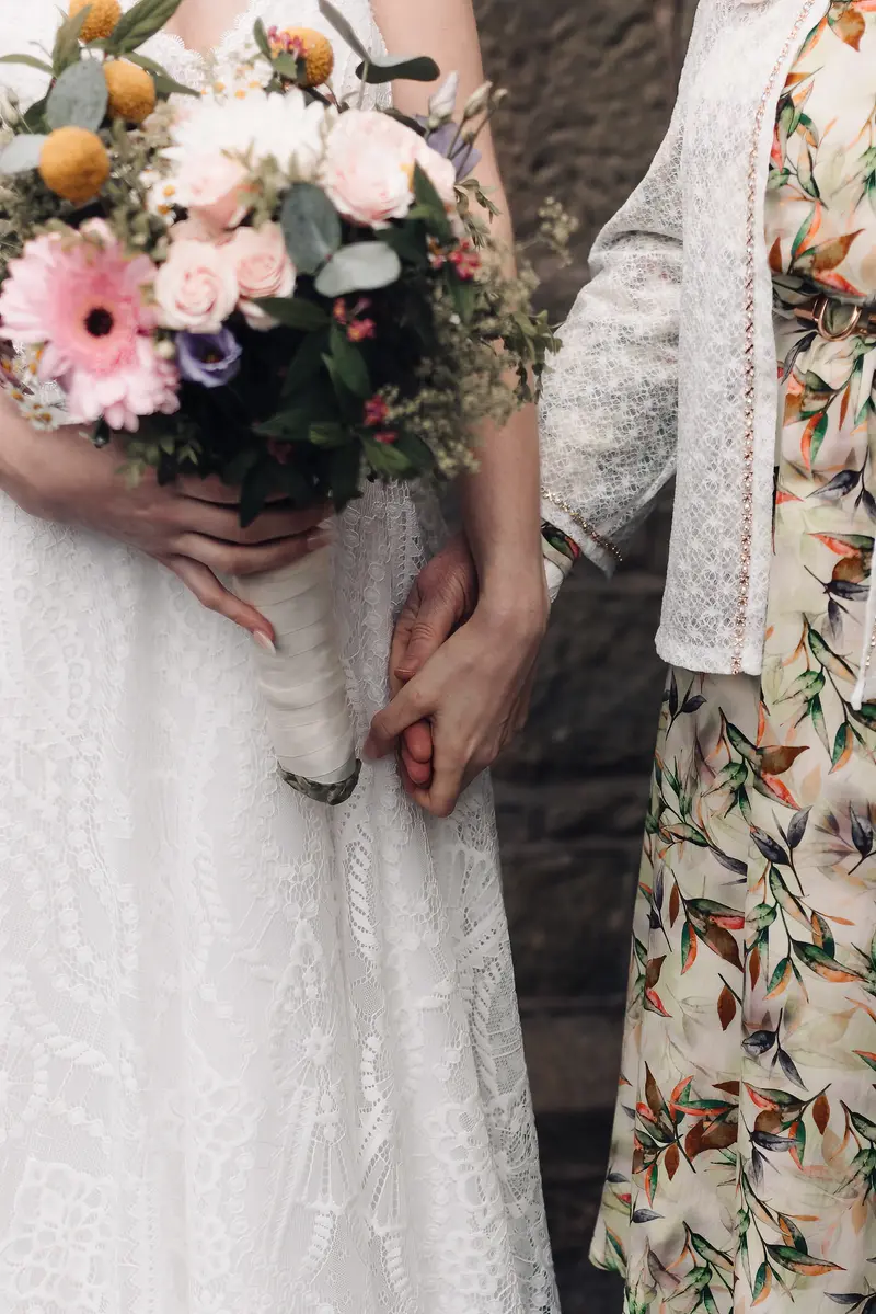 Close up bridal bouquet and emotional hand holding moment during wedding day