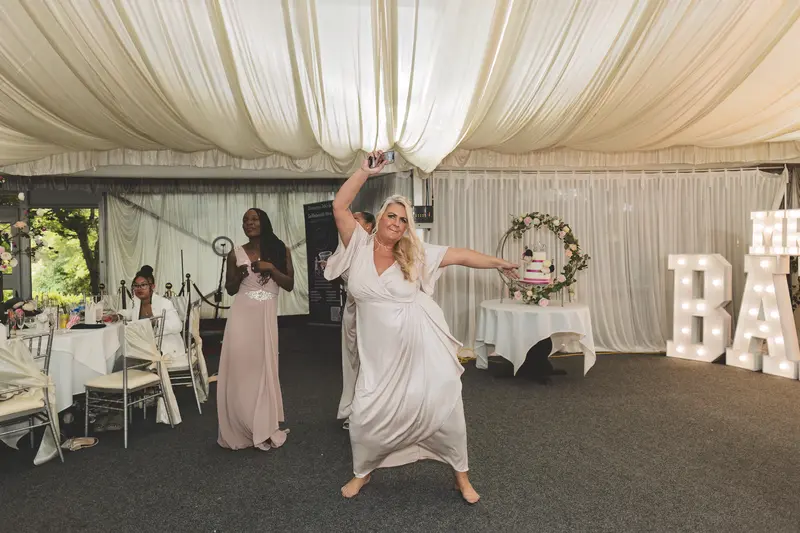 Bride dancing joyfully during the wedding reception with guests celebrating around her