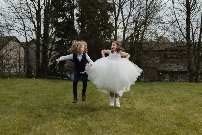 Documentary wedding photography of flower girl and page boy running together outdoors at Yorkshire wedding venue