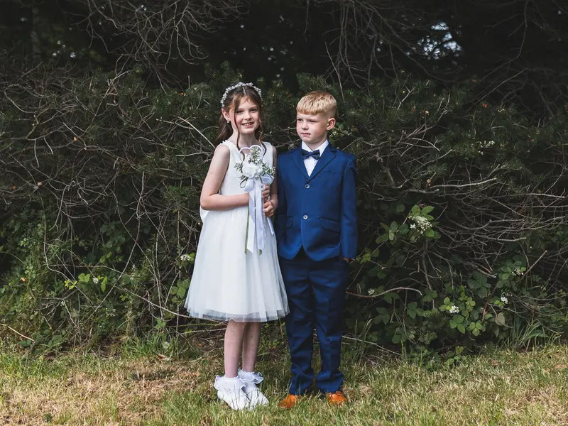 Flower girl and page boy smiling together during relaxed outdoor wedding portraits