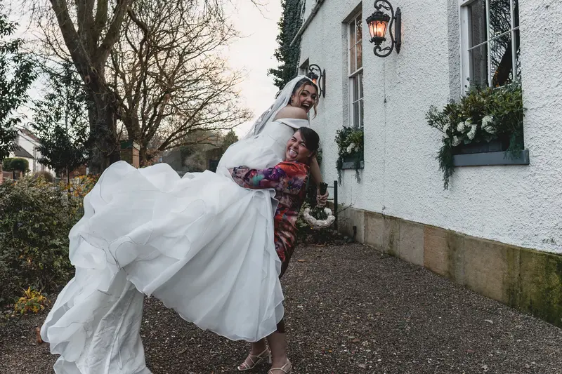 Bride laughing as she is lifted into the air during fun documentary wedding photography