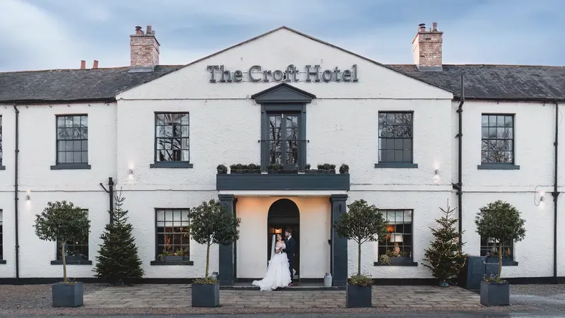 Bride and groom standing outside The Croft Hotel during romantic wedding portraits
