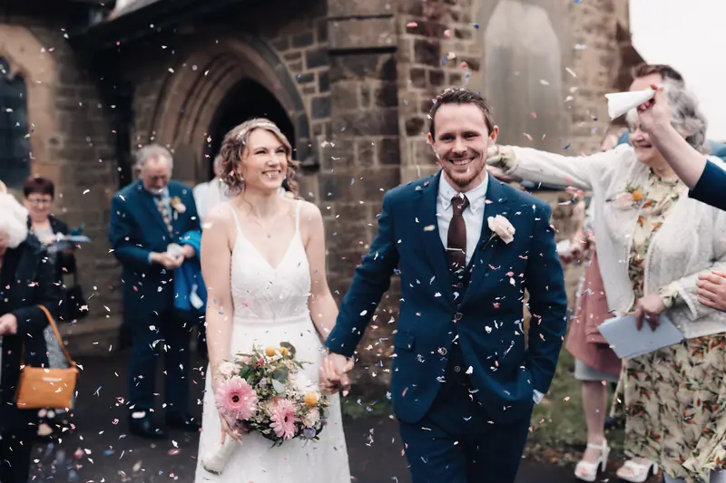 Joyful wedding confetti walk outside Yorkshire church captured in documentary style