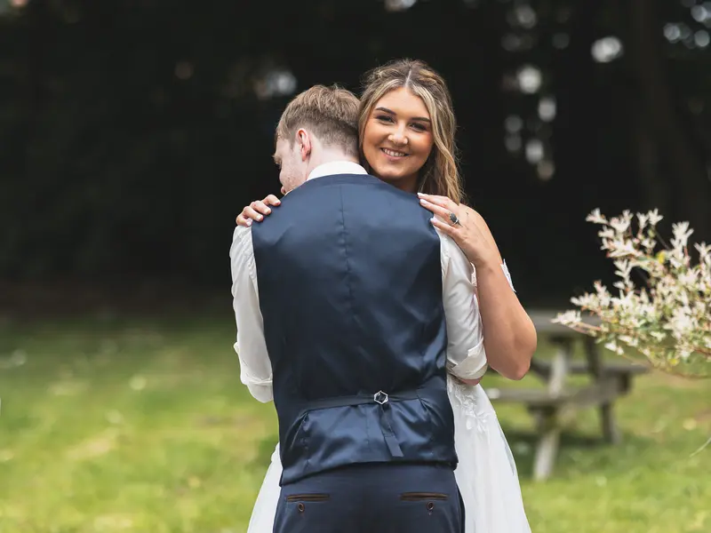 Bride smiling over the groom's shoulder during natural wedding portraits