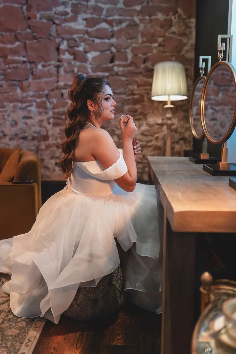 Bride applying lipstick during elegant bridal preparations before the wedding ceremony