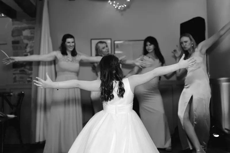 Black and white candid flower girl dancing with bridesmaids during wedding reception party in Yorkshire