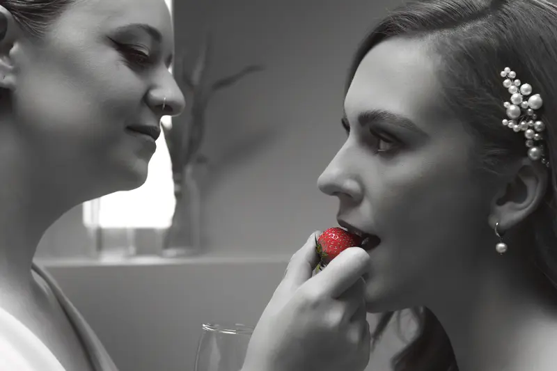 Artistic black and white lesbian wedding portrait with strawberry detail