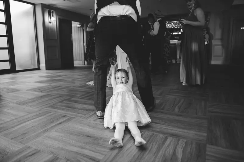 Black and white documentary wedding photo of toddler on dance floor