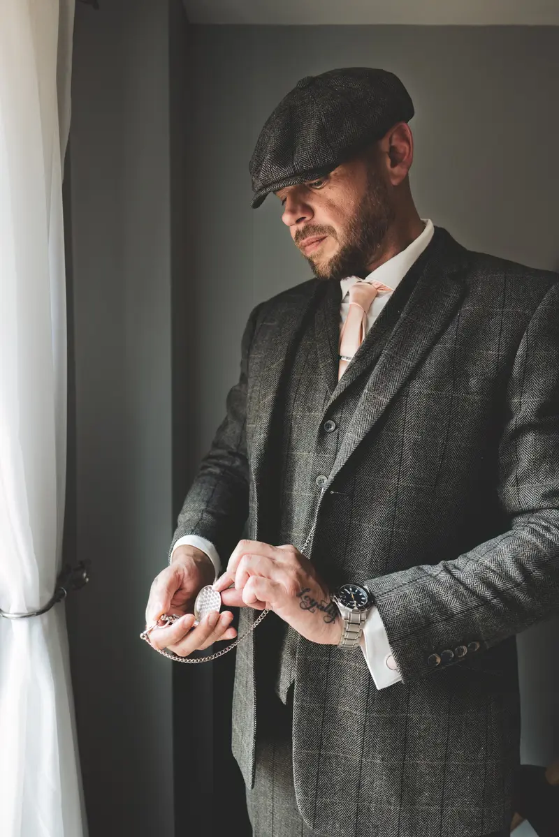 Groom adjusting his cufflinks by the window during elegant wedding morning preparations