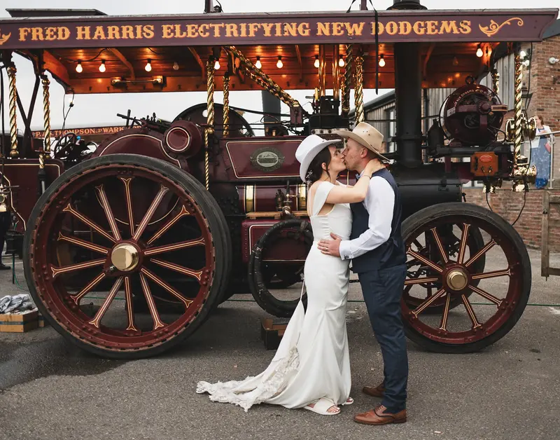 Romantic newlywed kiss in front of vintage steam engine wedding attraction