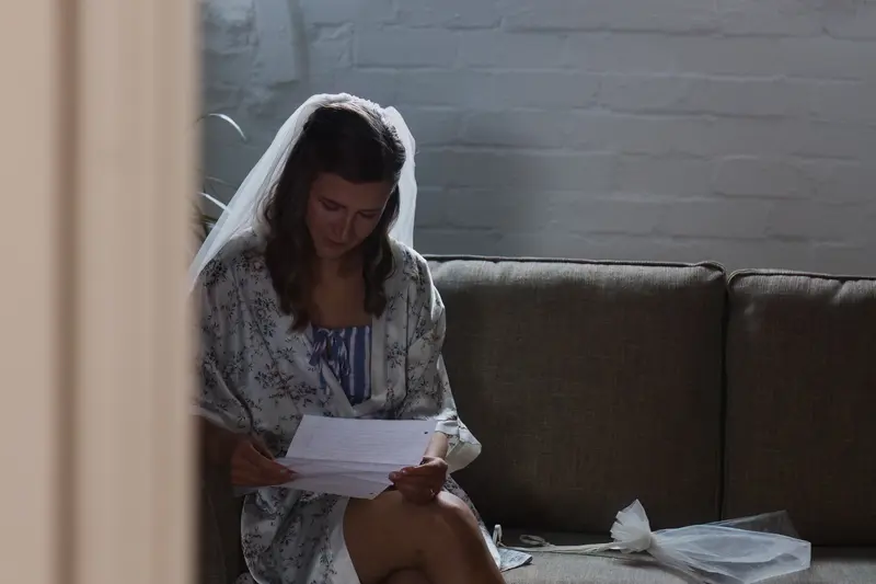 Emotional bride reading handwritten letter during quiet wedding morning preparations