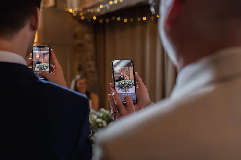 Guests capturing candid wedding moments on phones during Yorkshire wedding reception