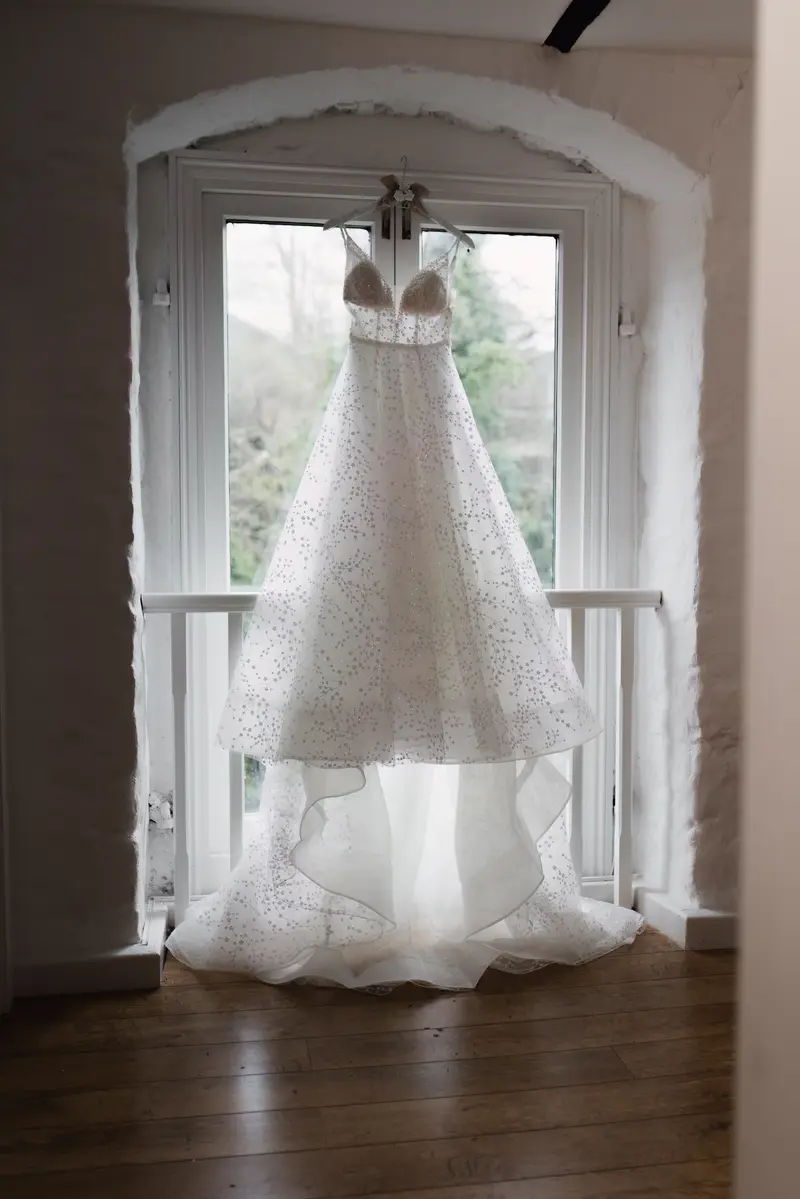 Elegant wedding dress hanging by window during Yorkshire bridal preparations
