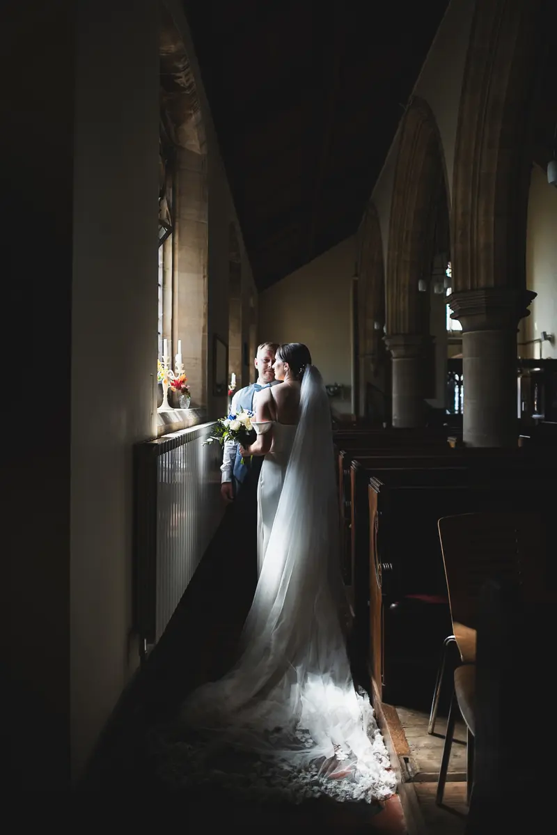 Dark and moody church wedding portrait with dramatic window light