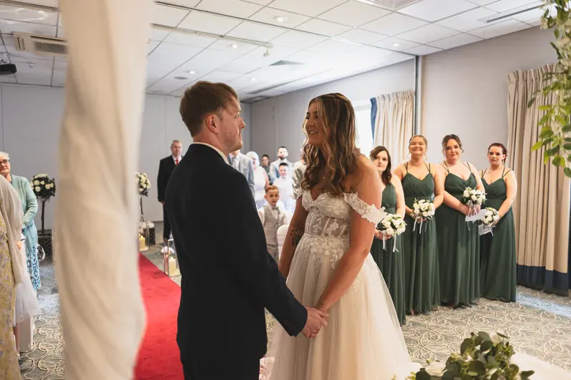 Bride and groom exchanging vows with guests watching during the ceremony