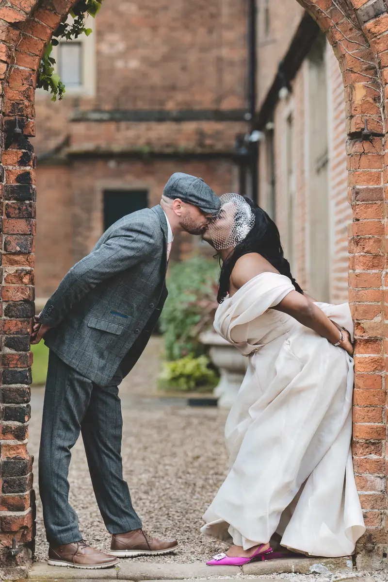 Groom kissing the bride during a fun romantic wedding portrait outside the venue
