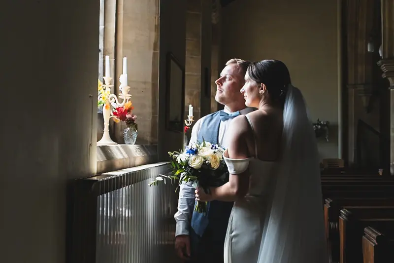 Elegant newlywed couple portrait with natural church window lighting