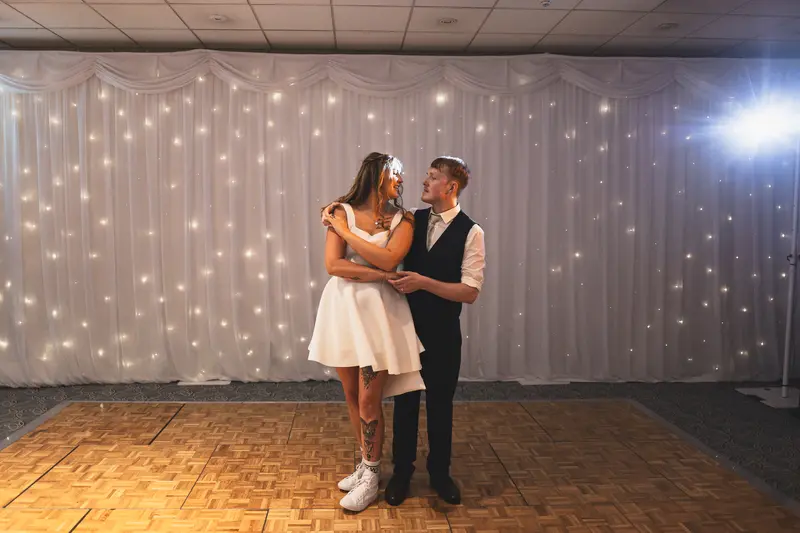 Bride and groom sharing their first dance beneath fairy lights
