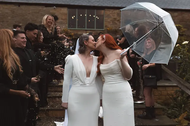 Romantic lesbian wedding kiss under umbrella with documentary style photography