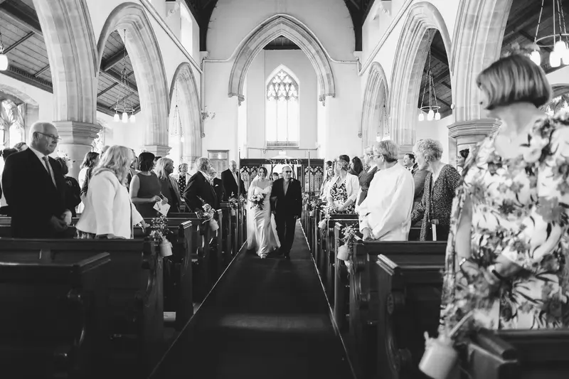 Bride walking down the aisle with father at church wedding ceremony