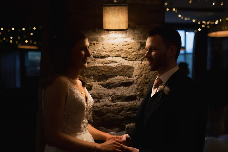 Moody documentary wedding portrait of bride and groom under warm reception lights at Yorkshire wedding venue